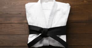 Martial Arts Uniform with Black Belt and Wooden Background