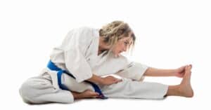 Female martial artist stretching with white background